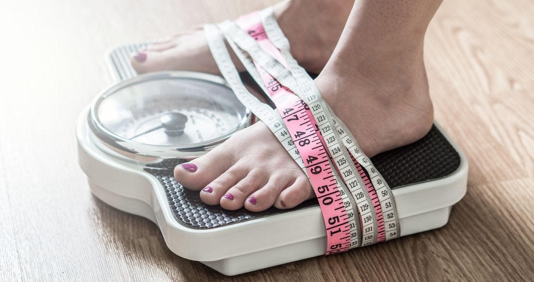 someone on a scale with measuring tapes draped around feet, Eating Disorder Recovery Strategies