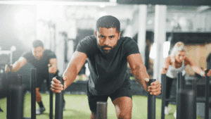 A focused man pushing a weighted sled during a workout, demonstrating willpower and self-control in physical training.