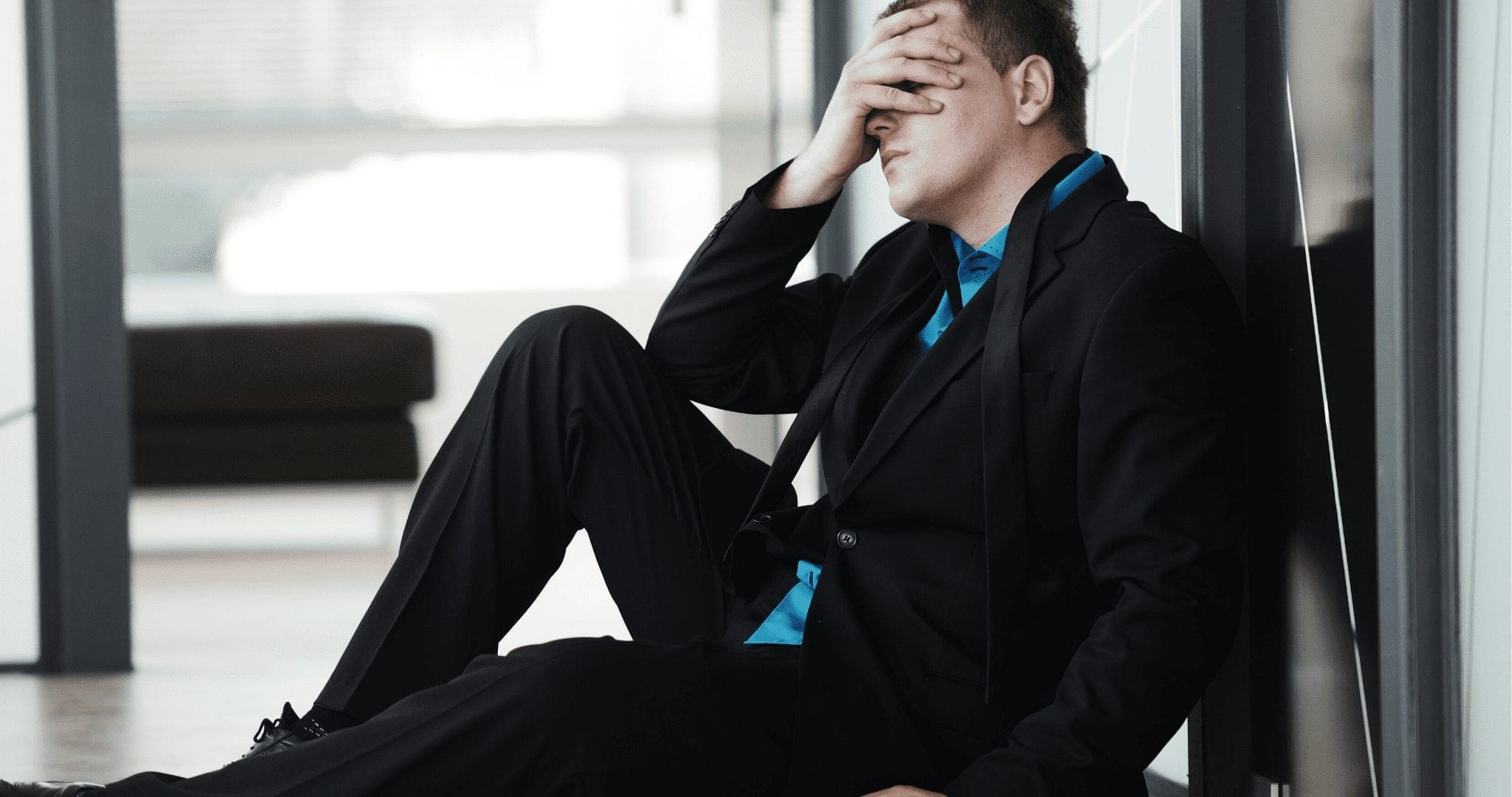 Man sitting on the floor holding his face feeling devastated, Coping with Disappointment