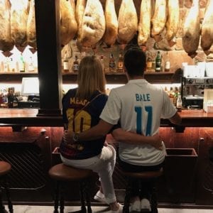Couple sitting at a bar wearing soccer jerseys