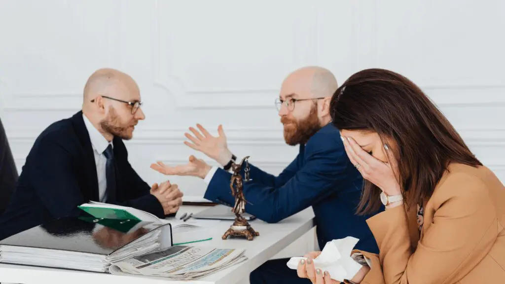 Stressed woman covering face while two businessmen argue during legal meeting, depicting people indecisive in conflict situations