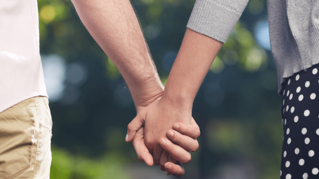 A couple holding hands, symbolizing connection and understanding without resorting to protest behaviors.