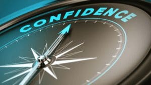 Picture of a watch with the hands pointing at the 12:00 position which says the word confidence