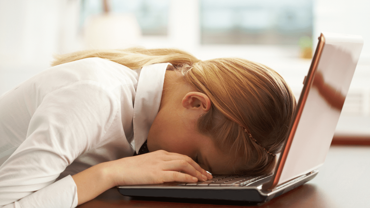 Brain-based coaching and counseling for mental exhaustion relief. Image of a woman resting her face on her laptop keyboard due to mental fatigue and needs neuroscience coaching.