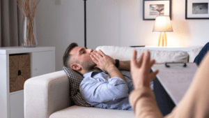 Strengthening Mental Resilience through Neuroplasticity Exercises A man laying on a couch receiving brain-based coaching from a professional, experiencing Mental Exhaustion and Fatigue