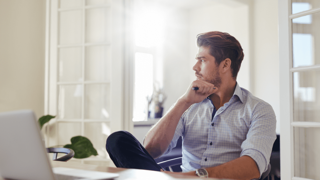 Man in deep thought at desk, contemplating personal growth and neuroplasticity through brain-based coaching techniques.