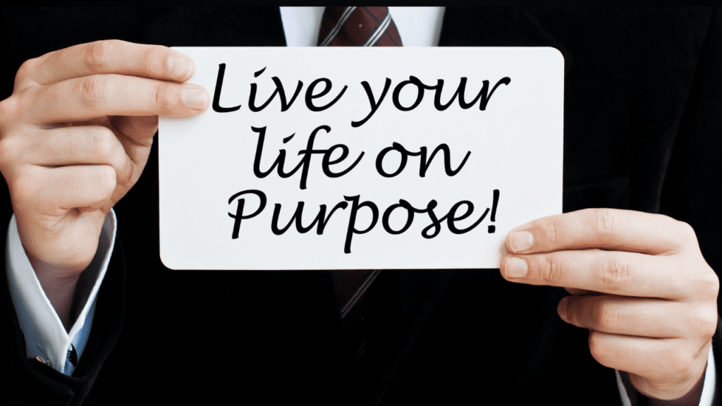 Man holding a 'live your life on purpose' sign after discovering his life's passion and purpose and adopting a positive mindset through brain-based life coaching.