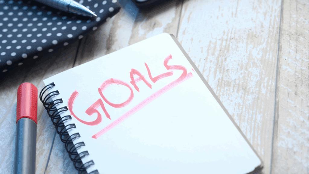 Boosting Self-Drive: Strategies for Achieving More 1 Close-up of a notepad with the word “Goals” written in red, representing the concept of a self-driving goal.