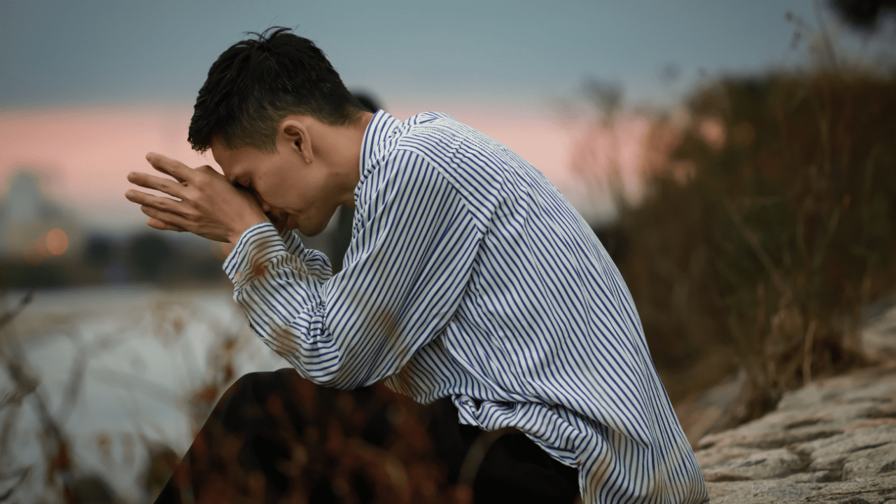 Man holding head in hands, depicting struggle with depression and dysthymia, emphasizing the importance of understanding differences and overcoming the disorders.