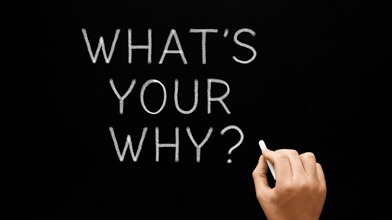 Man writing 'What's your why?' on chalkboard, searching for life coaching guidance to find his passion, discover his purpose, and adopt a positive mindset