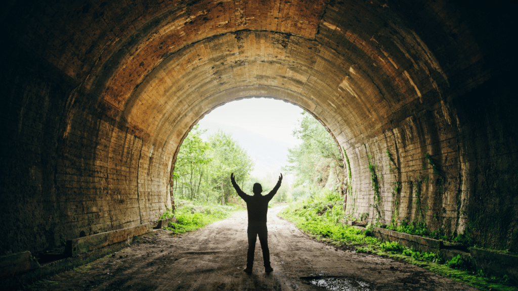 Man in tunnel with arms raised in victory, symbolizing triumph over depression and dysthymia, and the importance of understanding their differences for successful recovery.