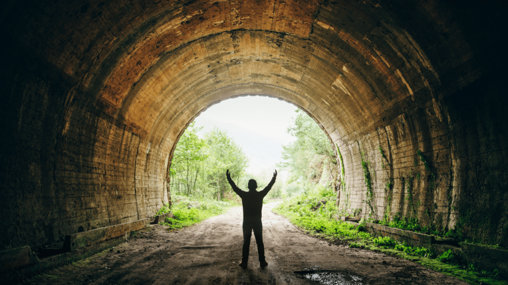 Victorious Man Overcoming Depression and Dysthymia: Understanding Key Differences and Finding a Cure Man in tunnel with arms raised in victory, symbolizing triumph over depression and dysthymia, and the importance of understanding their differences for successful recovery.
