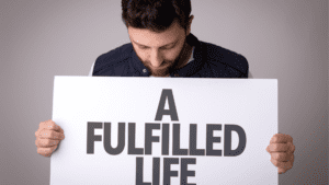 Man holding a 'fulfilled life' sign after life coaching, neuroplasticity, brain-based coaching, and positive habits for fulfillment