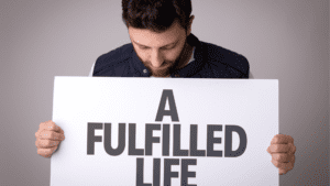 Man Holding Sign: Living a Fulfilled Life through Life Coaching and Brain-Based Coaching Techniques Man holding a 'fulfilled life' sign after life coaching, neuroplasticity, brain-based coaching, and positive habits for fulfillment