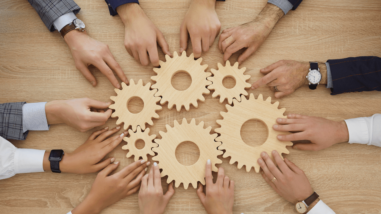 Group of people assembling gears symbolizing the 7 habits of highly effective people.