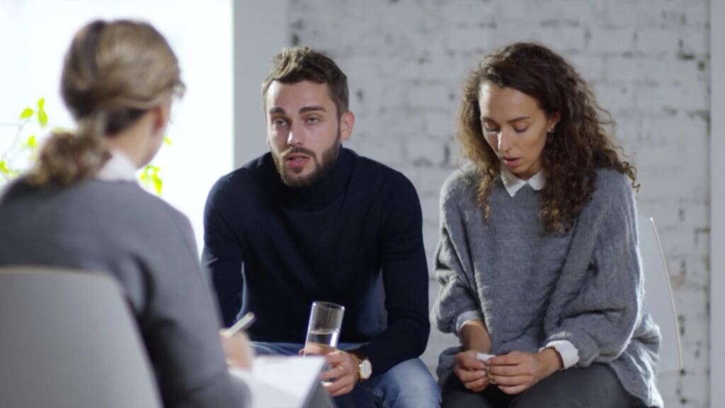 Couple engaged in neuroscience-based marriage counseling session, discussing relationship challenges with a counselor.