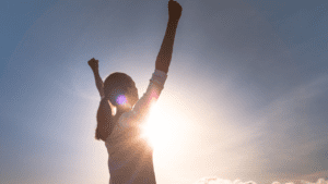 Woman raising her hand in victory after regaining her confidence and self-worth. Cheating impacts self-esteem