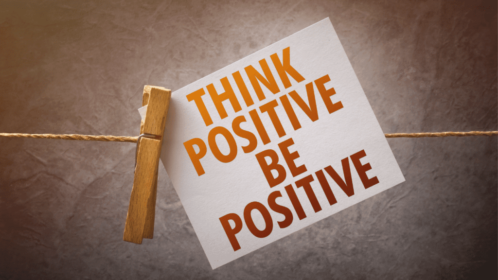 White paper with the words "Think positive, be positive" written on it.