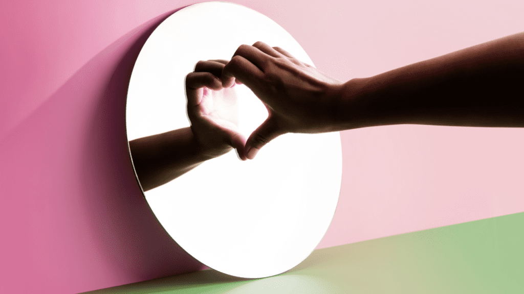 Hand making a heart symbol against a round mirror, signifying overcoming relationship phobia