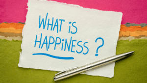 Colorful sign posing the thought-provoking question 'What does it mean to be happy?' with additional text on 'Understanding happiness' and 'Achieving happiness in life', indicating an exploration of happiness concepts.