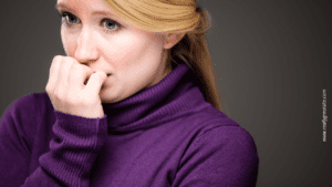 Woman biting nails, depicting communication anxiety and need for life coaching, self-improvement strategies for addressing fear and self-doubt in social interaction.
