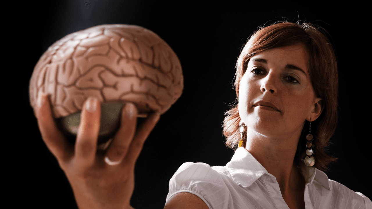 Woman holding a brain model, symbolizing her interest in Brain-Based Coaching, MindLAB Neuroscience Coaching, and the benefits of Neuroscience Life Coaching