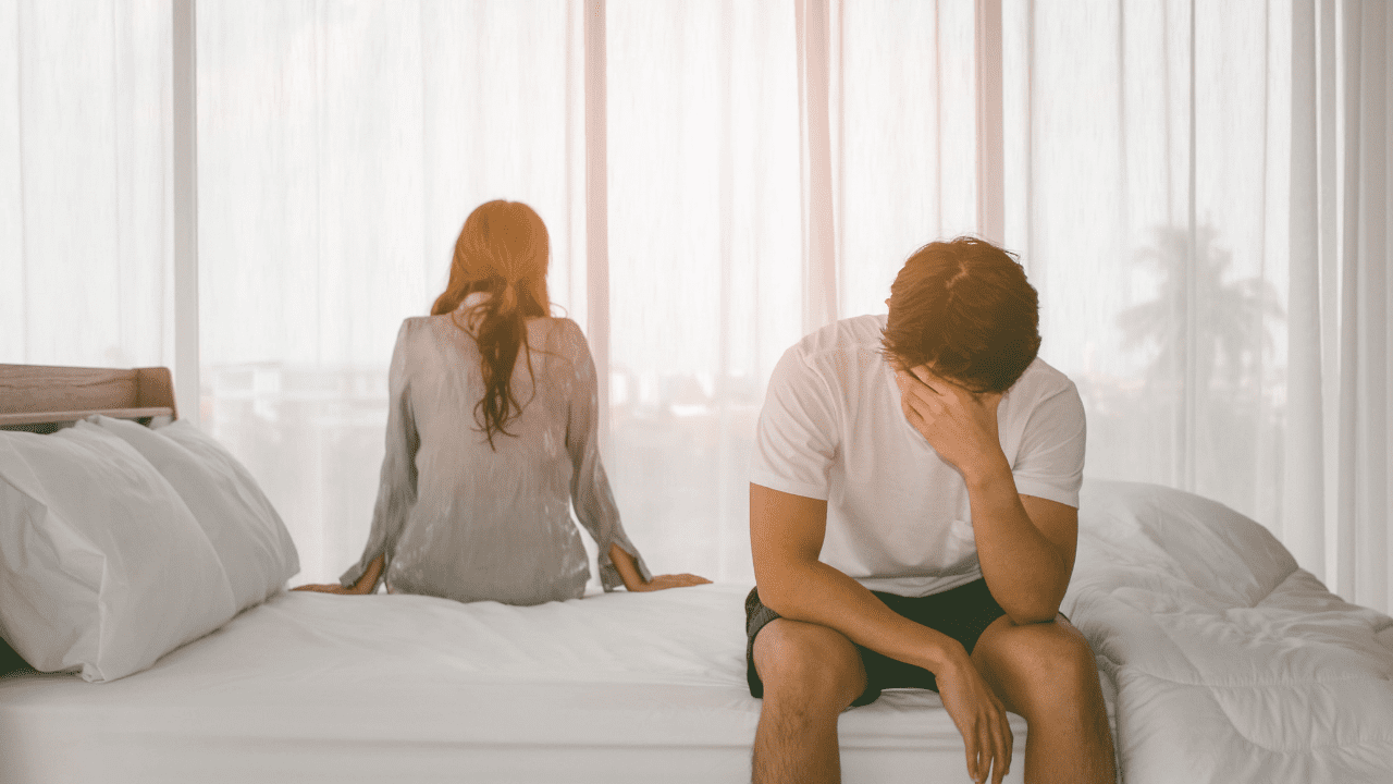 Unhappy couple on opposite sides of bed, indicating the need for a relationship counselor