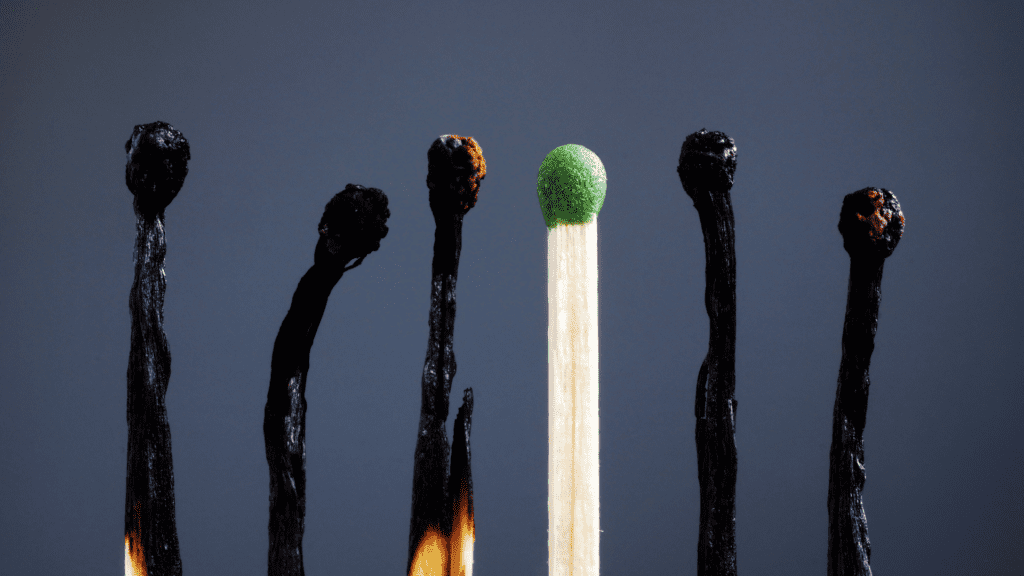 Burnt matches stand out from a single green match, symbolizing burnout and standing out from the crowd.