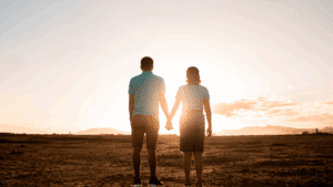 Embracing Vulnerability: How Your Flaws Can Strengthen Your Relationship 2 Couple holding hands while facing the sunset, symbolizing Embracing Vulnerability and connection.