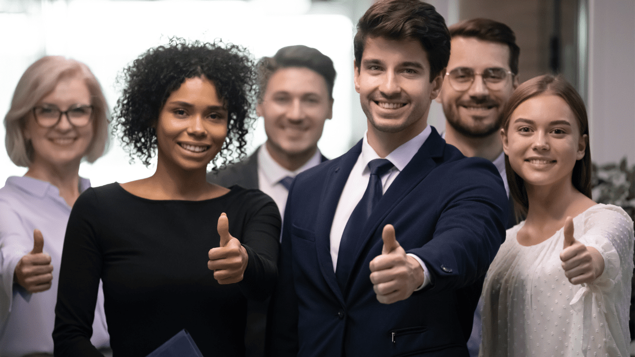 Group of satisfied men and women giving thumbs up after life and career coaching session