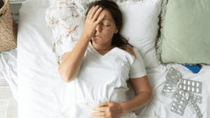 Woman laying in bed covering her face, suffering from depression due to negative self-talk