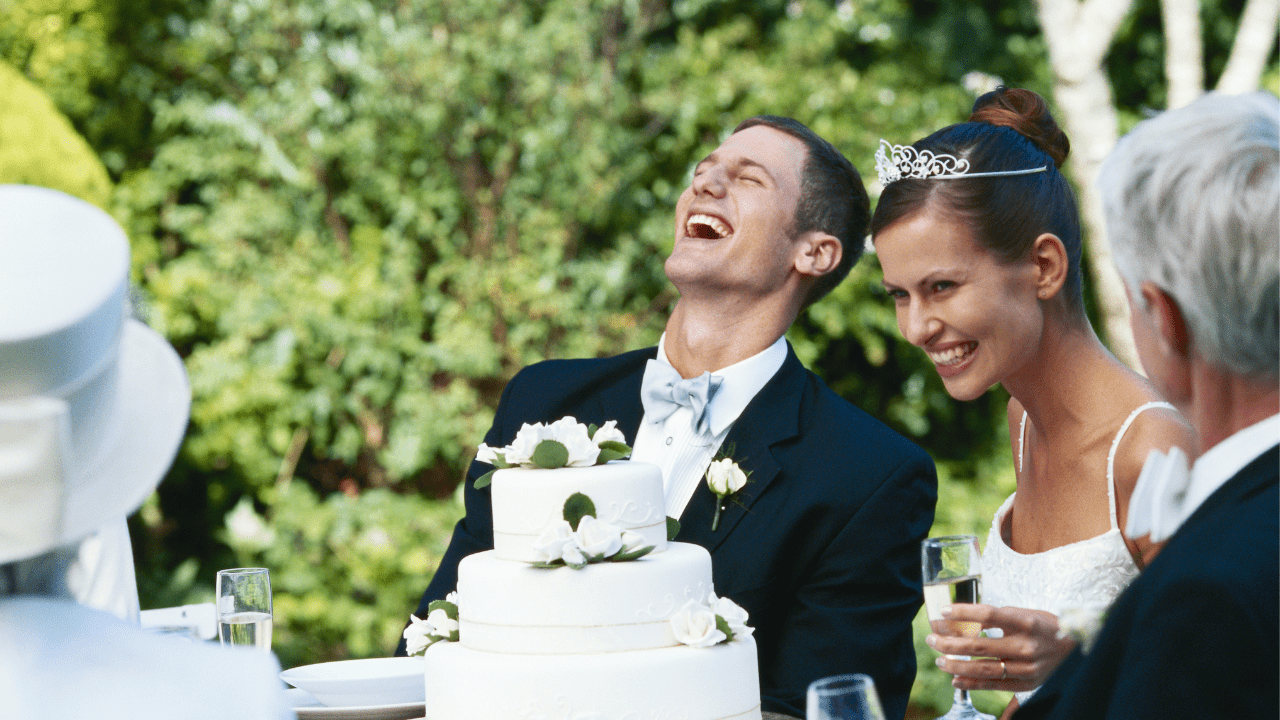 Newlywed couple at their wedding, sitting at a table with their wedding cake, symbolizing the importance of marriage counseling in building a solid marital foundation.