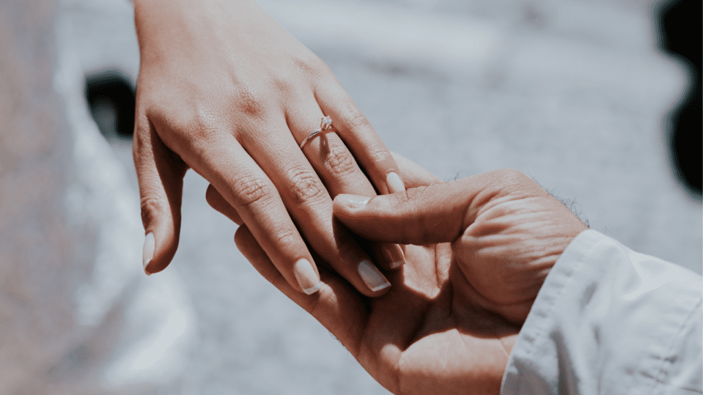 Newlywed couple holding hands with wedding rings, symbolizing the importance of marriage counseling for building a solid marital foundation.