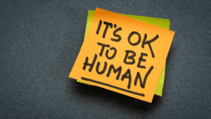 Sticky note with the message 'It's okay to be human', symbolizing embracing vulnerability and imperfections