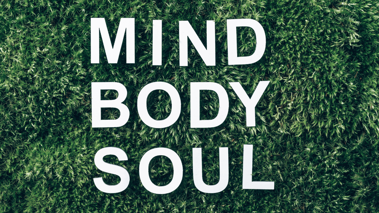 White letters spelling 'Mind Body Soul' in green grass, representing the benefits of whole person coaching