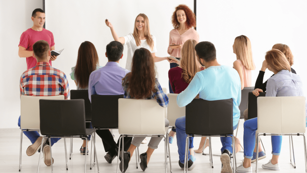 Group of people attending a team training session to work on cognitive distortions that are affecting their team dynamics.
A group of employees attentively participating in a training session led by two facilitators, emphasizing the role of education and awareness in overcoming cognitive distortions within teams.
