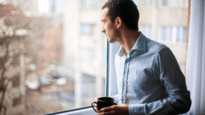 Man contemplating psychological needs while looking out the window.