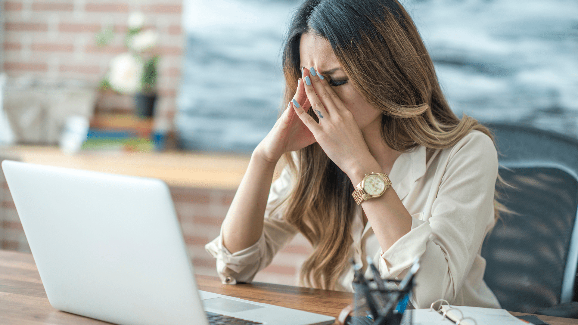 Stressed woman at desk with laptop, emphasizing the need for neuroplasticity stress reduction