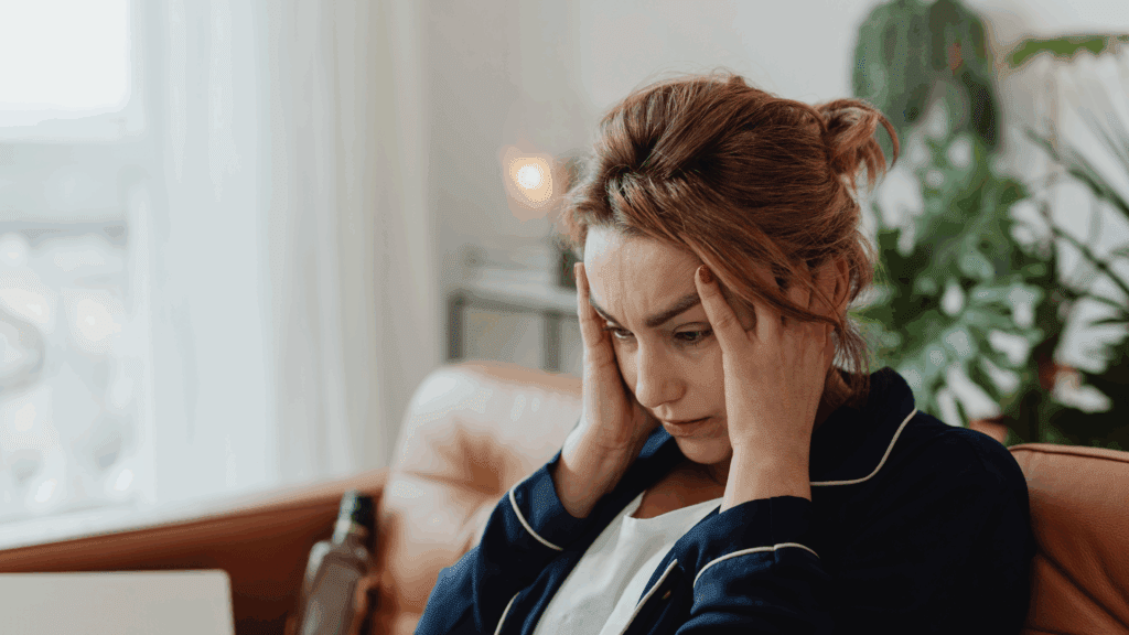 Neuroplasticity and Cognitive Restructuring 3 Stressed woman holding her head, symbolizing the role of neuroplasticity and cognitive restructuring in managing negative thoughts.