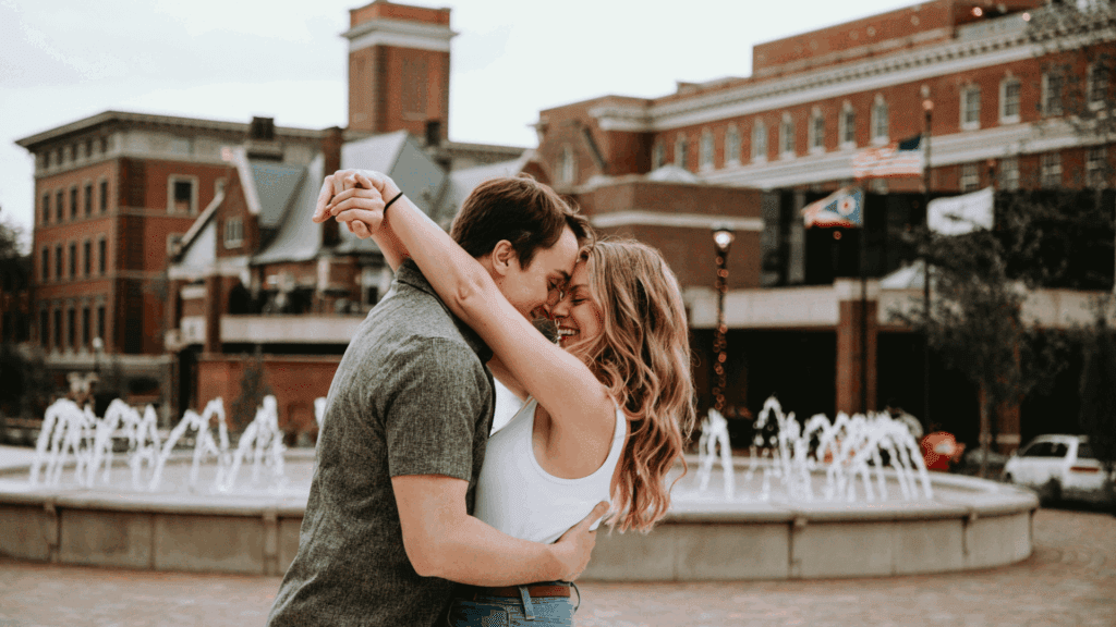 Understanding the Role of Neuroscience in Love Biases 2 A smiling couple embracing near a fountain, symbolizing connection and the influence of neuroscience in love biases.
