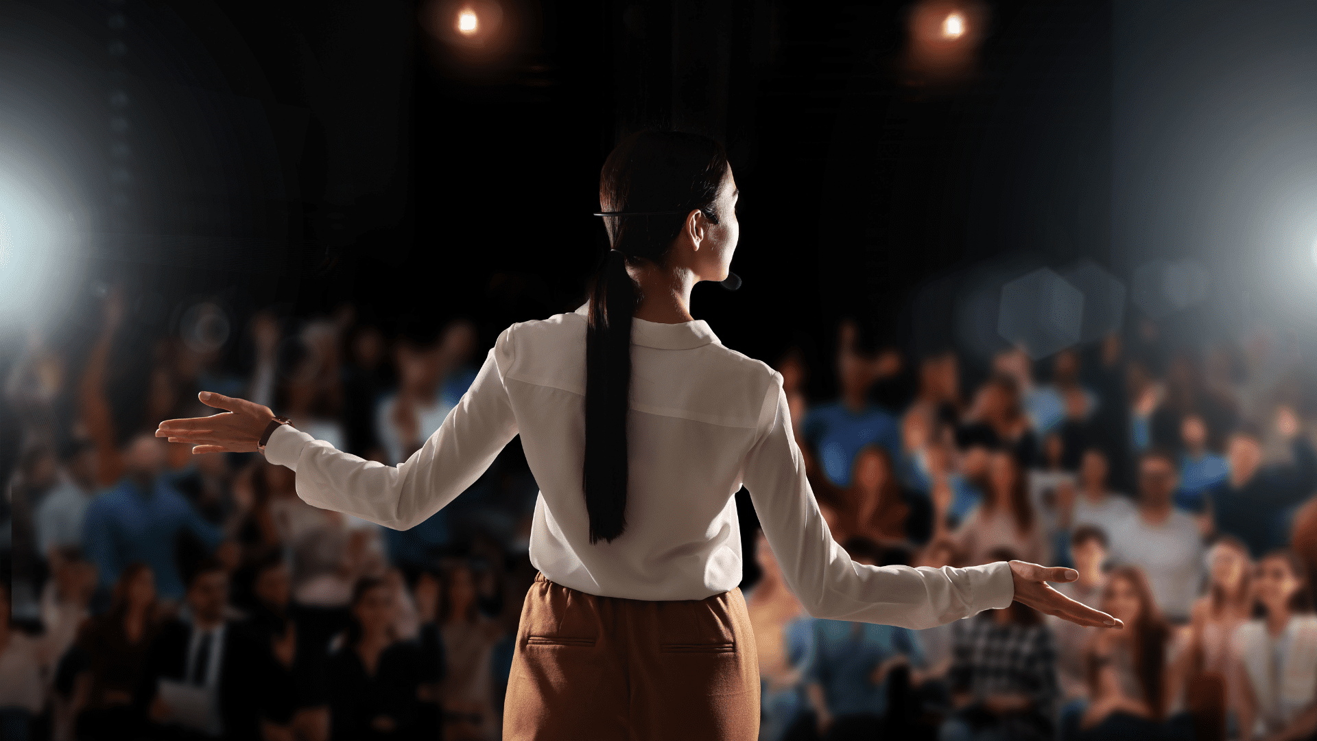 Young female motivational speaker addressing fear of public speaking on stage.