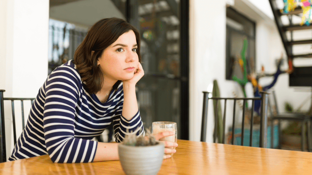 a woman sitting at a table with a cup of milk who is lonely and experiencing feelings of loneliness