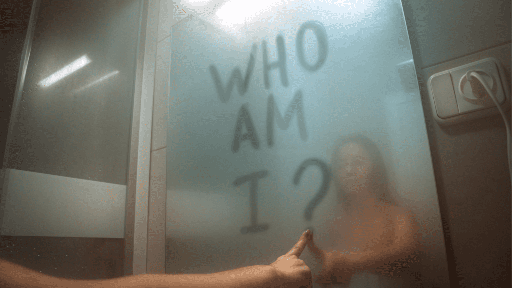 a person standing in a shower with a hand pointing at a glass door searching for her Core Identity