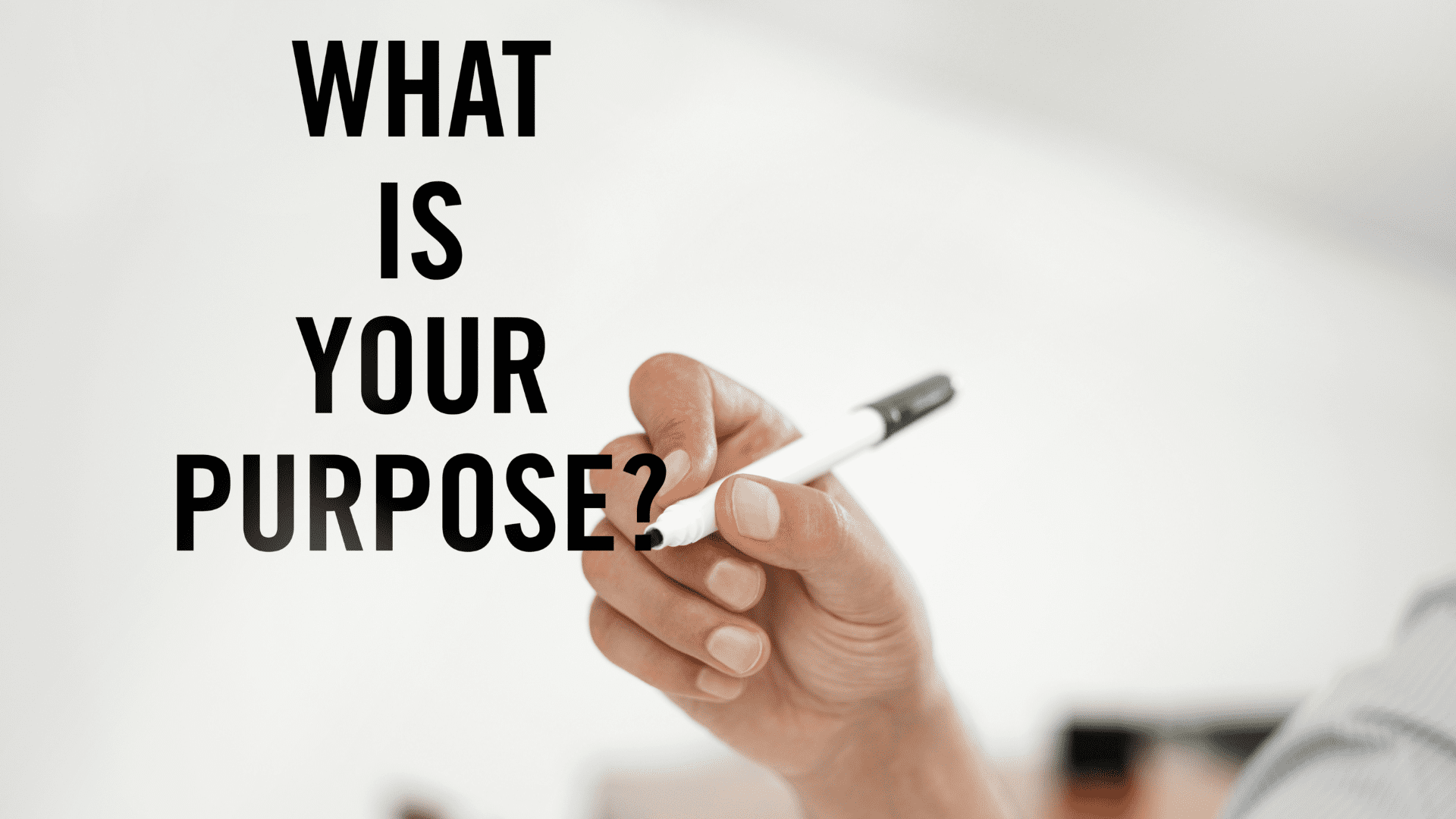 a hand holding a pen with the words What is your purpose?