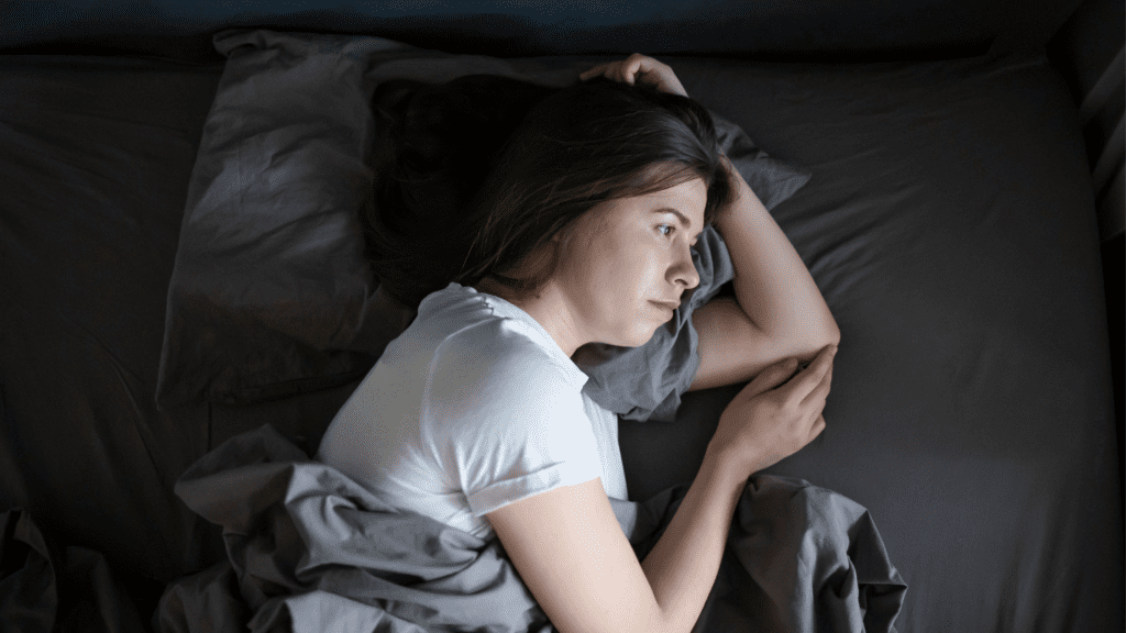 a woman lying in bed having constant intrusive thoughts and in need of neuroscience-based treatment