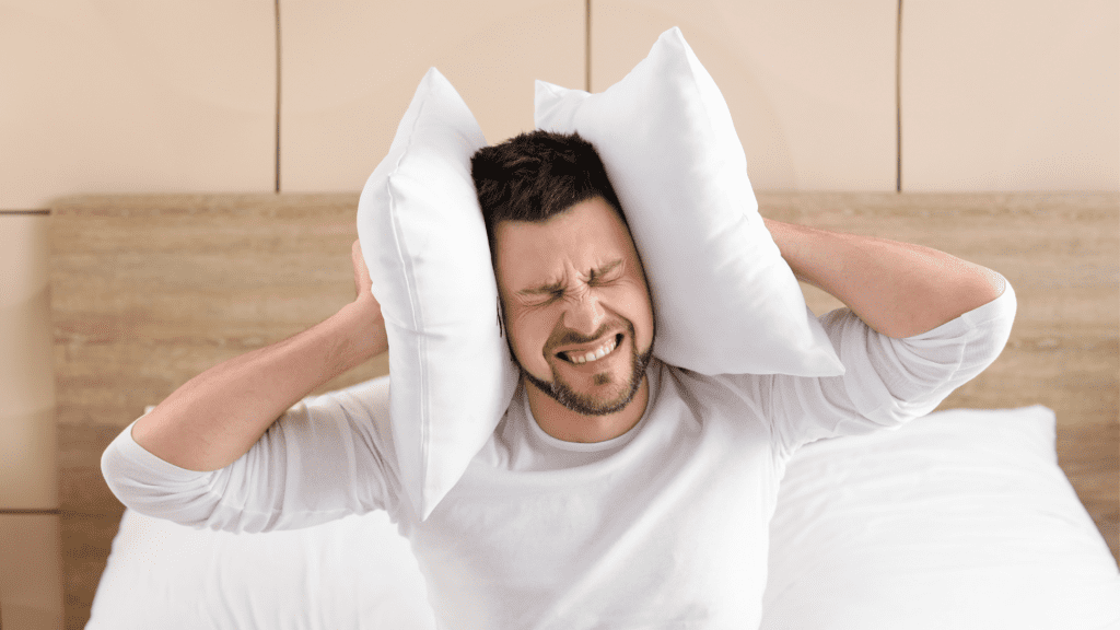 man suffering from constant intrusive thoughts holding a pillow over his ears