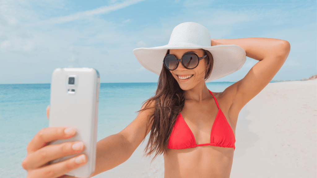 A woman who is a narcissist taking a selfie of herself at the beach.