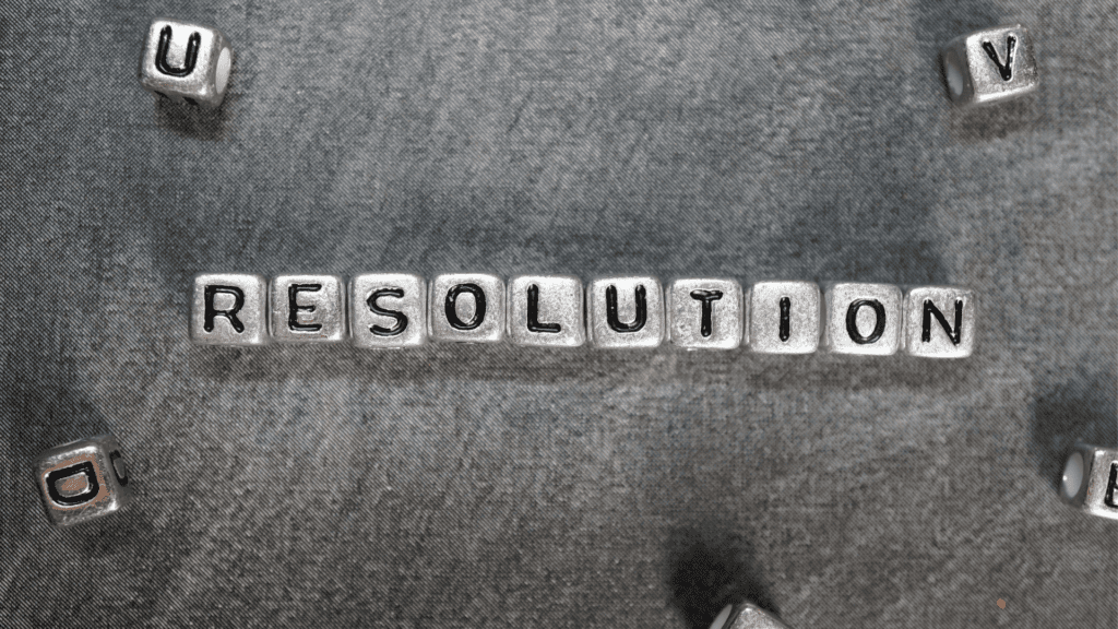 The word "Resolution" spelled out with metallic letter blocks on a gray background, emphasizing constructive conflict.