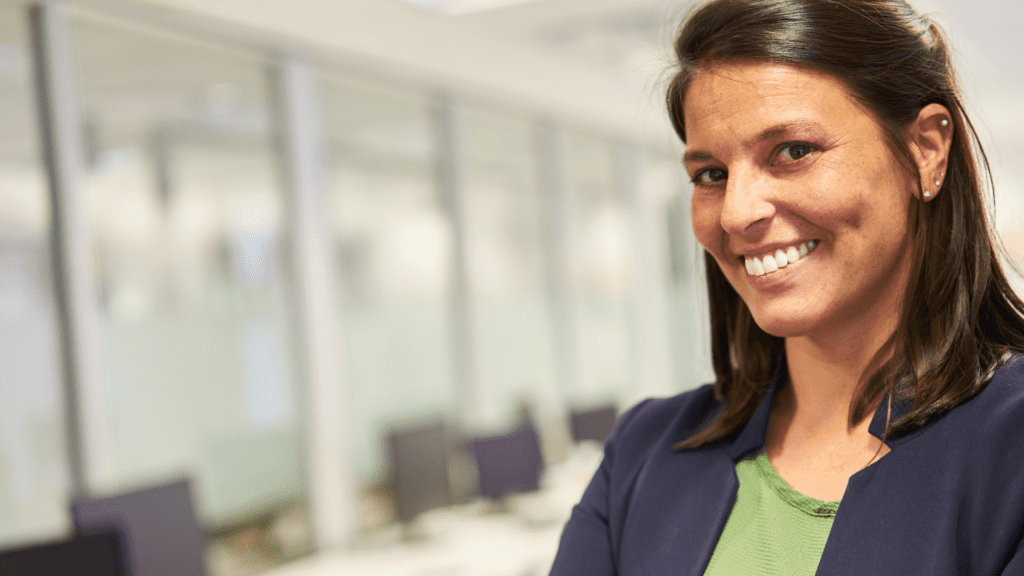 Confident woman smiling in an office setting.
