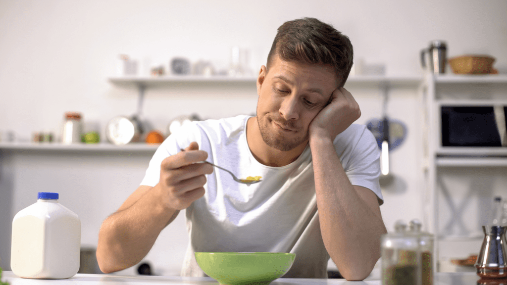 A man eating cereal alone, reflecting loneliness in a sexless marriage.